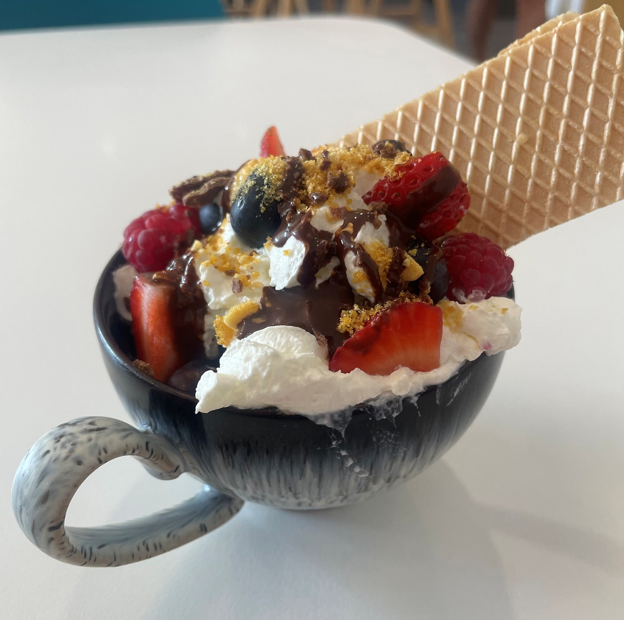 Icecream sunday in a cofee cup with cream and sprinkles and wafer